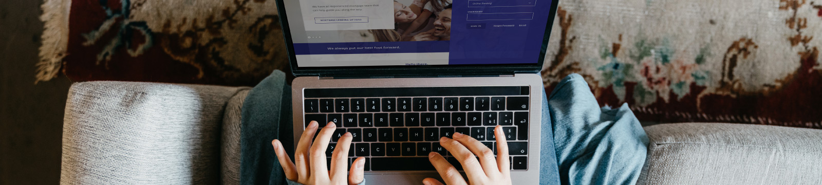 Woman sitting on a couch with laptop showing Commercial Bank's website.