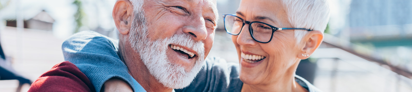 Mature man and woman sitting close to one another laughing.