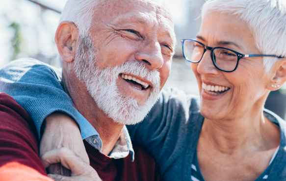 Mature couple sit close laughing.