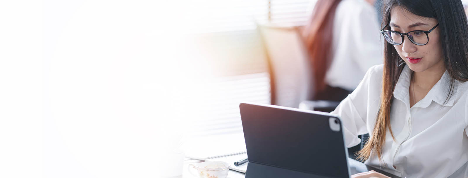 A lady is sitting at a desk working on a computer. 